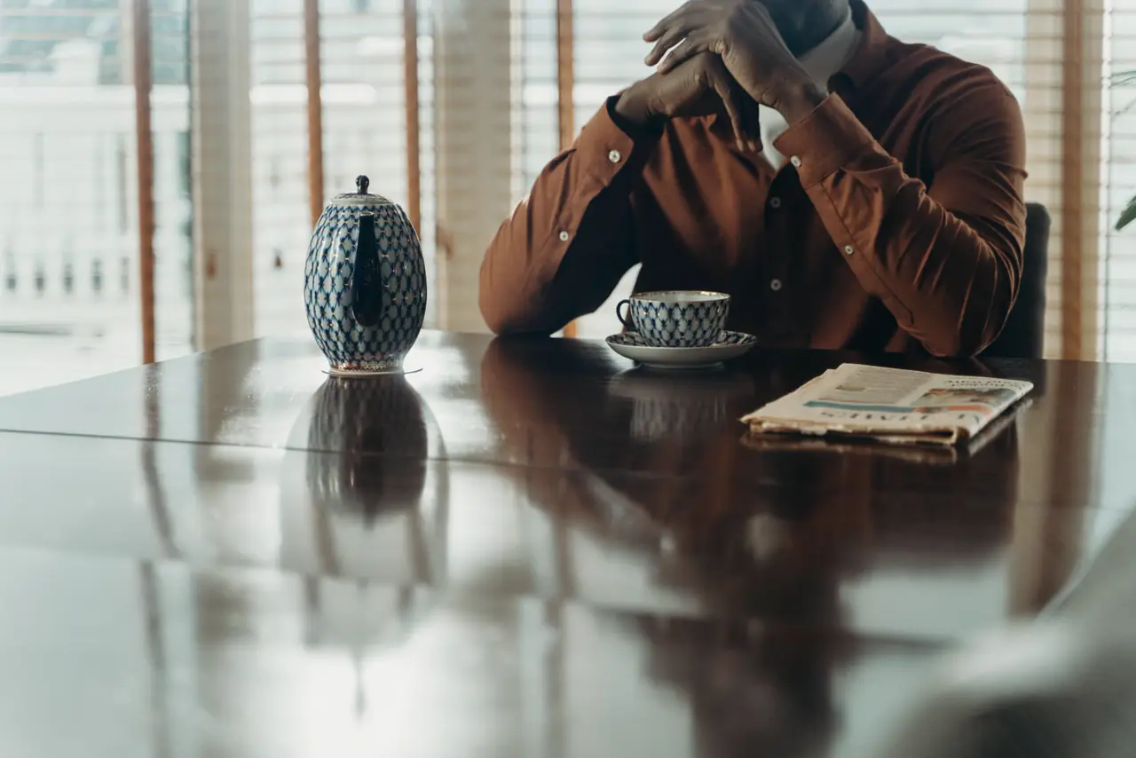 A folded local newspaper on a table beside a teapot and cup.